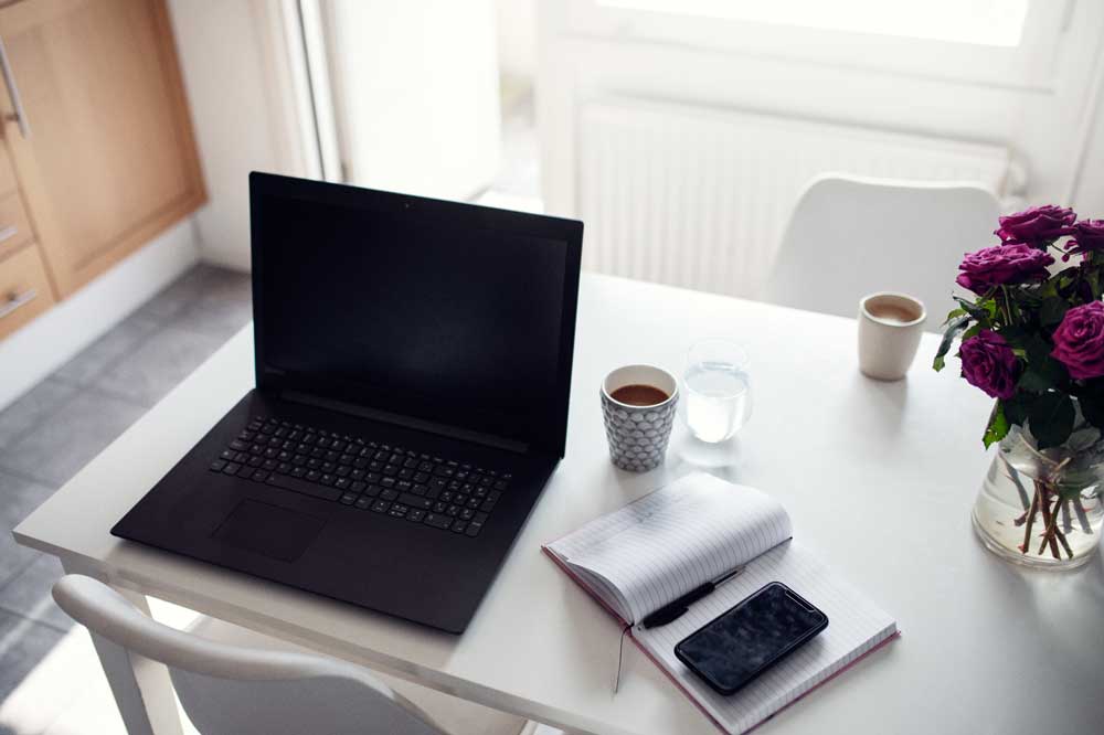 em laptop  på ett bord med ett block och en mugg